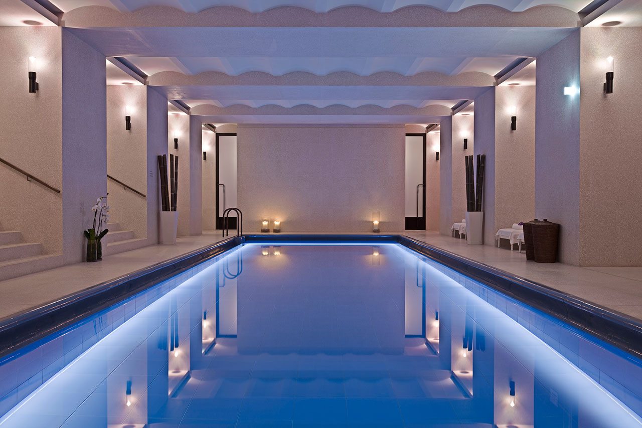 Blue indoor swimming pool with low lighting