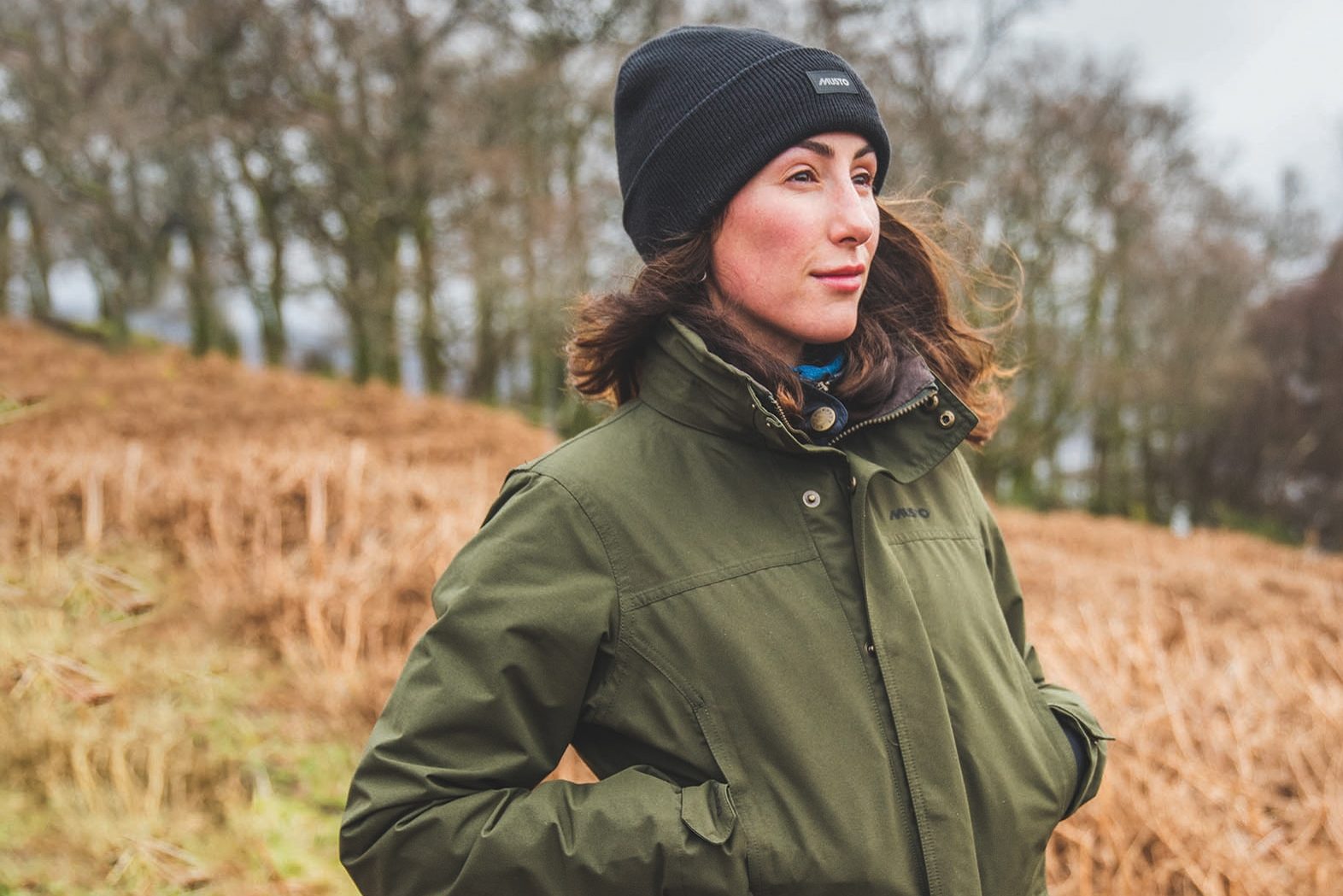 Brunette woman in Khaki Musto jacket and black beanie - British Sporting Brands
