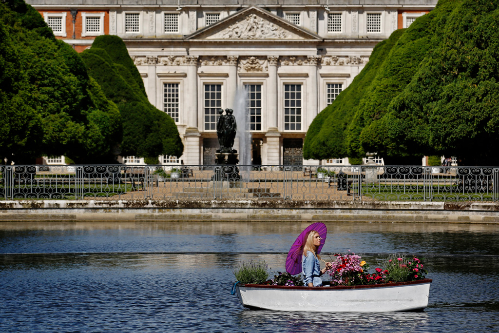 RHS employee rows pots of flowers accross the Long Water at the RHS Hampton Court Palace Flower Show.