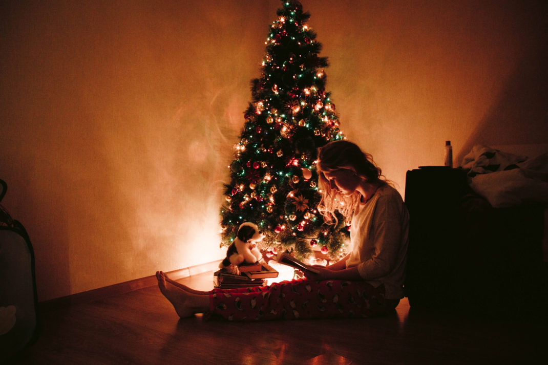 Reading a book beside a glowing Christmas tree