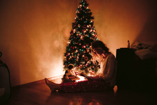 Reading a book beside a glowing Christmas tree