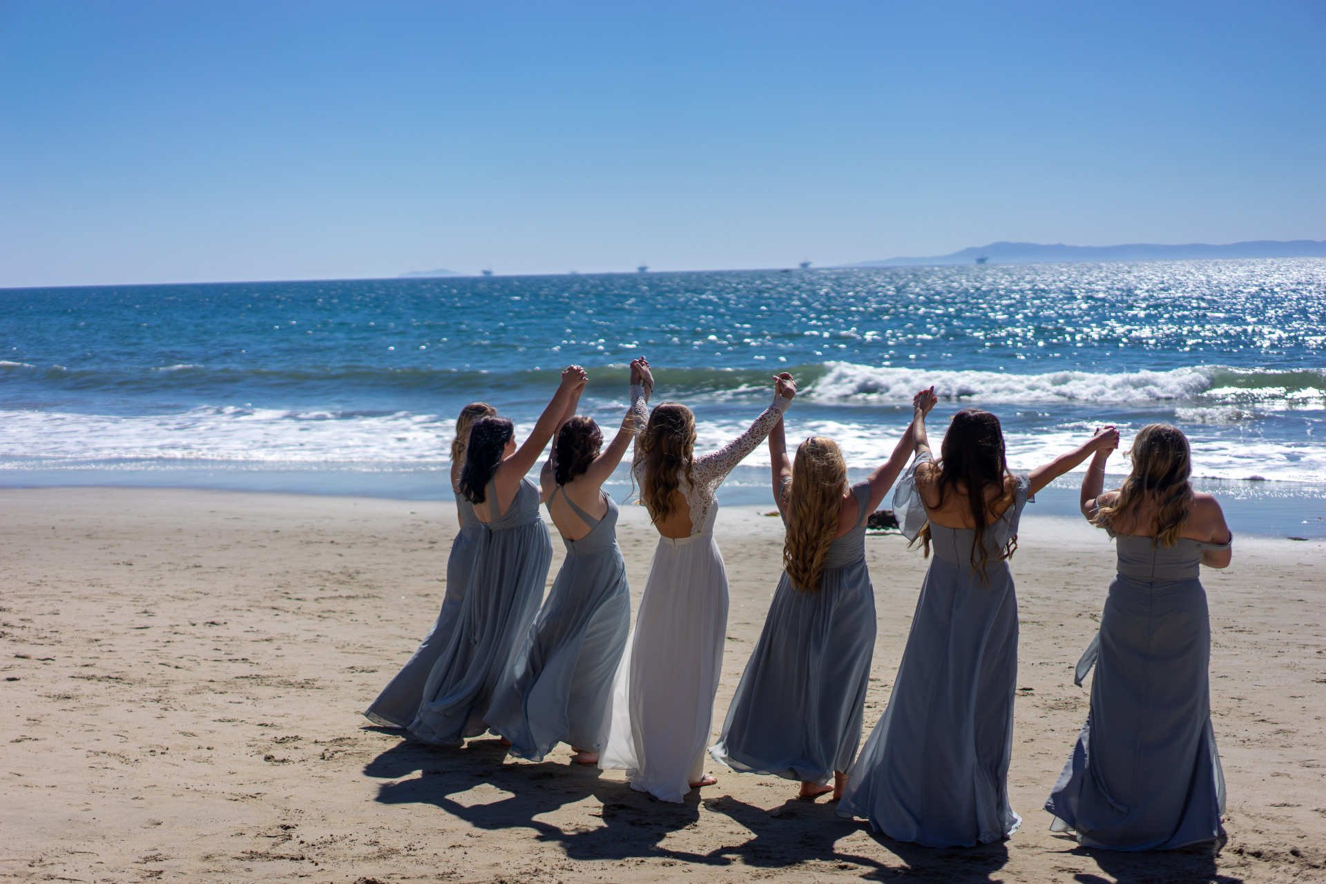 Brides and bridesmaids on the beach in the sun