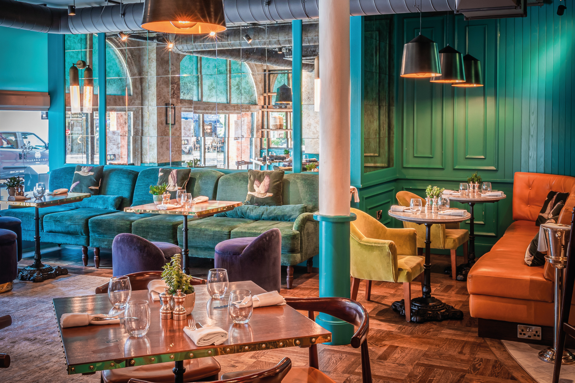 Restaurant with turquoise wood panelling and sofas, wooden tables and chairs