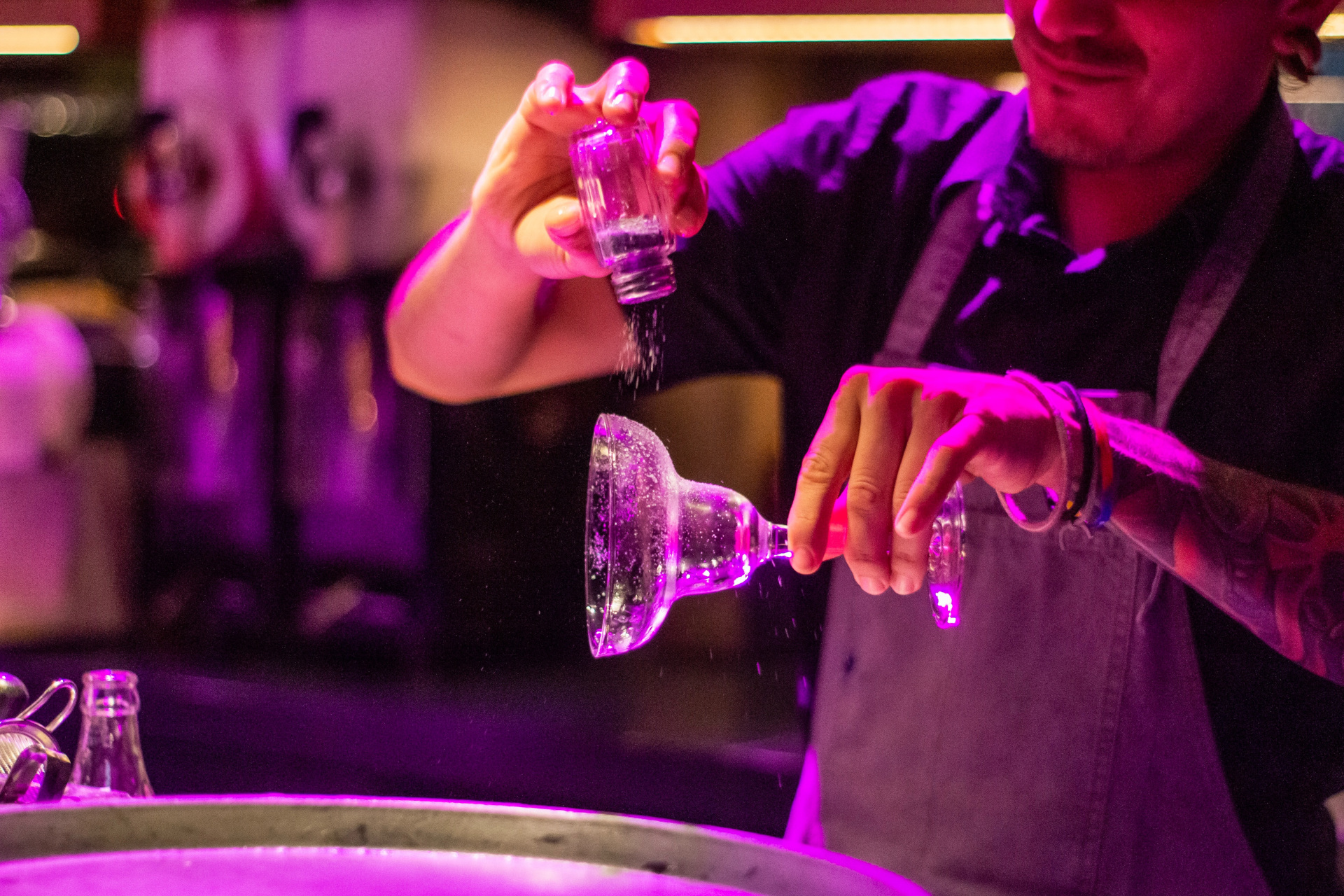 Bartender poring salt on cocktail glass