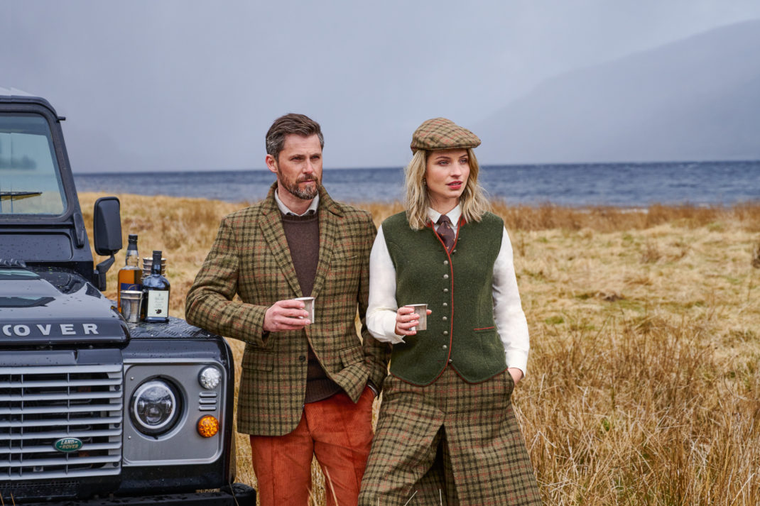 Two models in country clothing next to a landrover