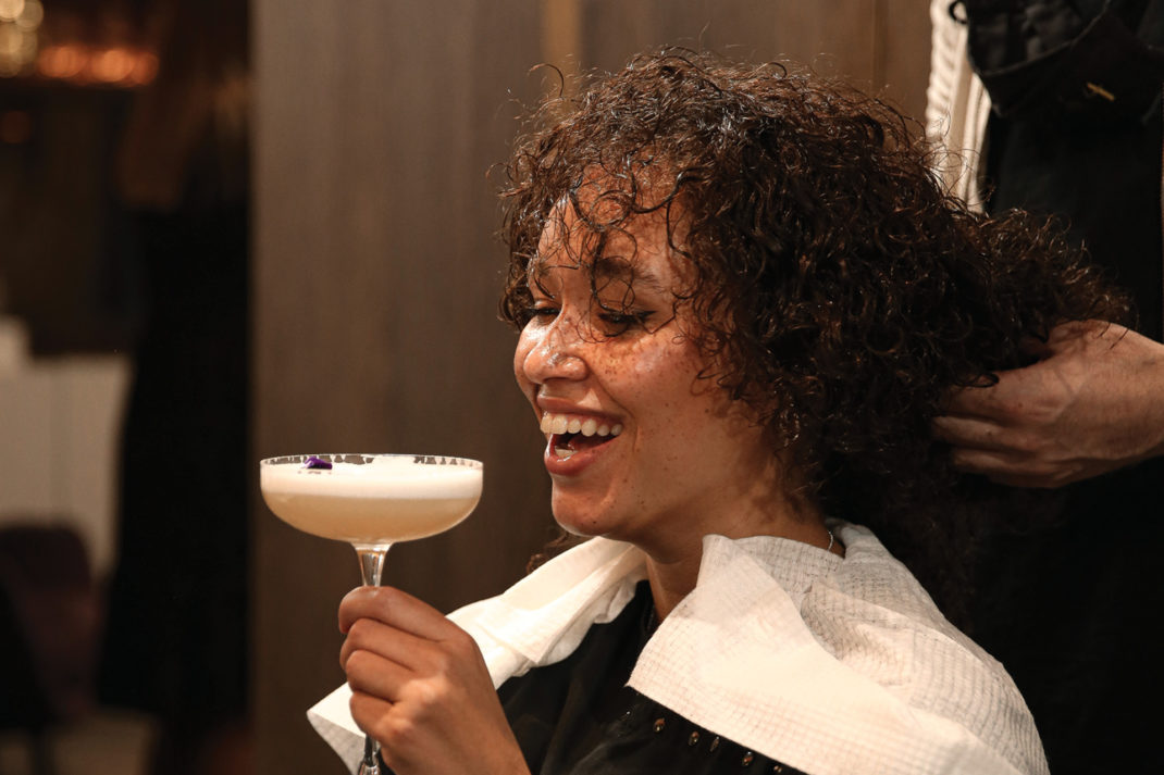 Woman with a cocktail getting her hair done