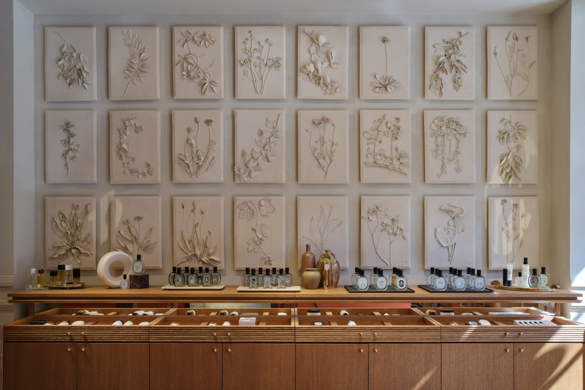 Wall mounted with floral tiles over wooden sideboard stocked with perfumes