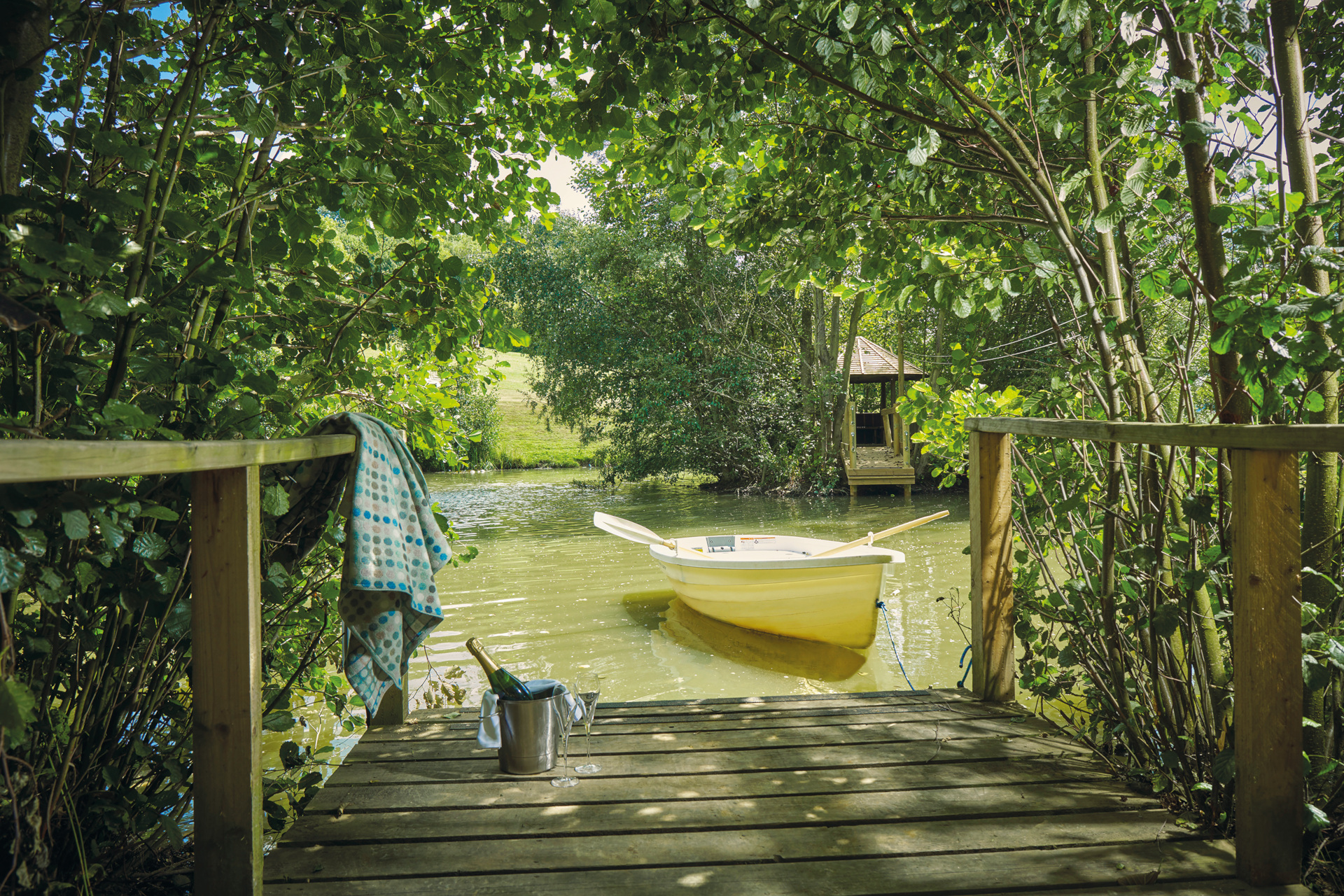 View of lake from decking with rowboat and bucket of fizz
