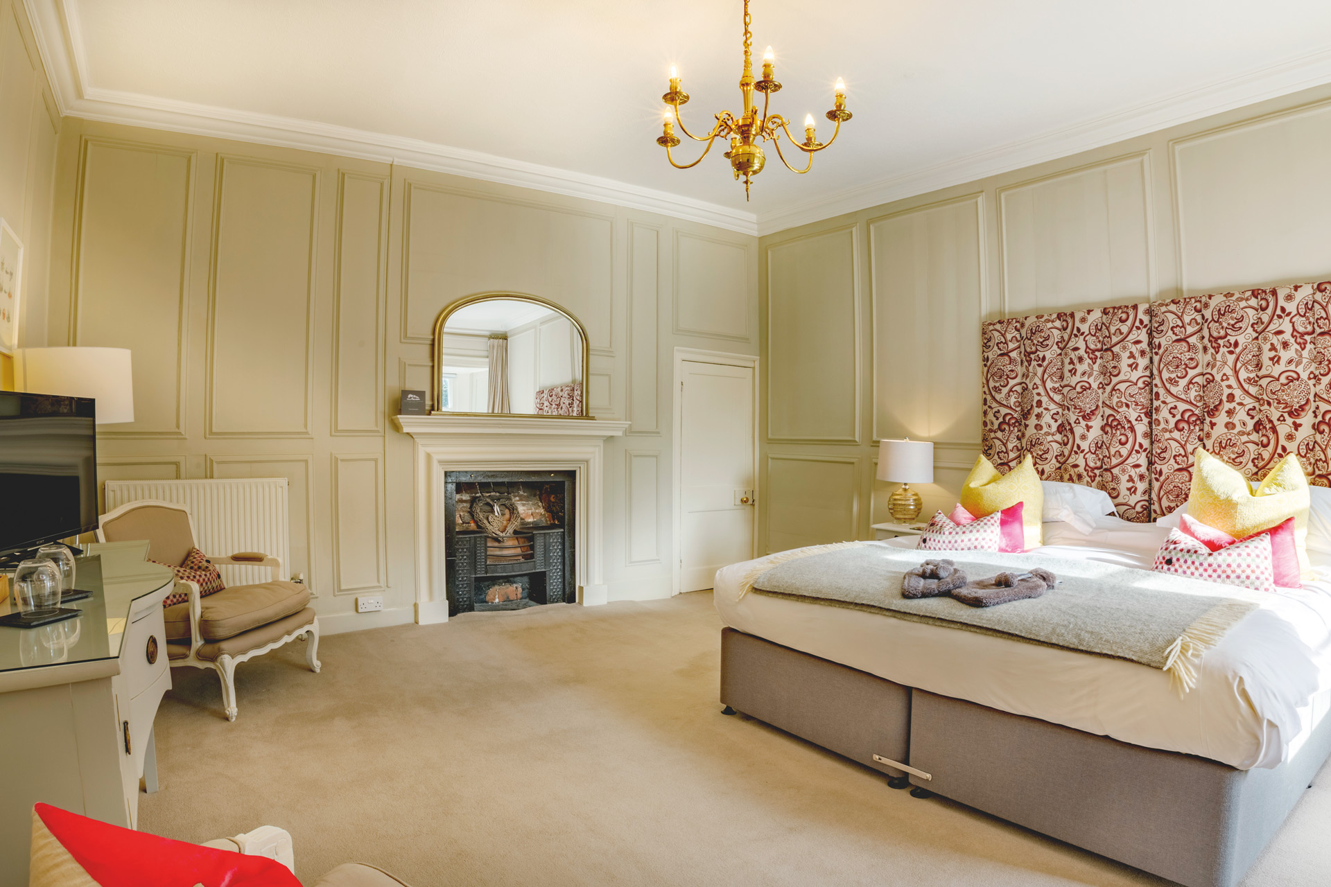 Bedroom at Trewornan Manor with a patterned headboard and a fireplace.