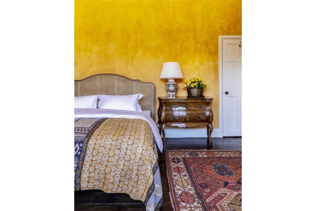 Blyth Collinson designed bedroom with yellow walls, bed and rug