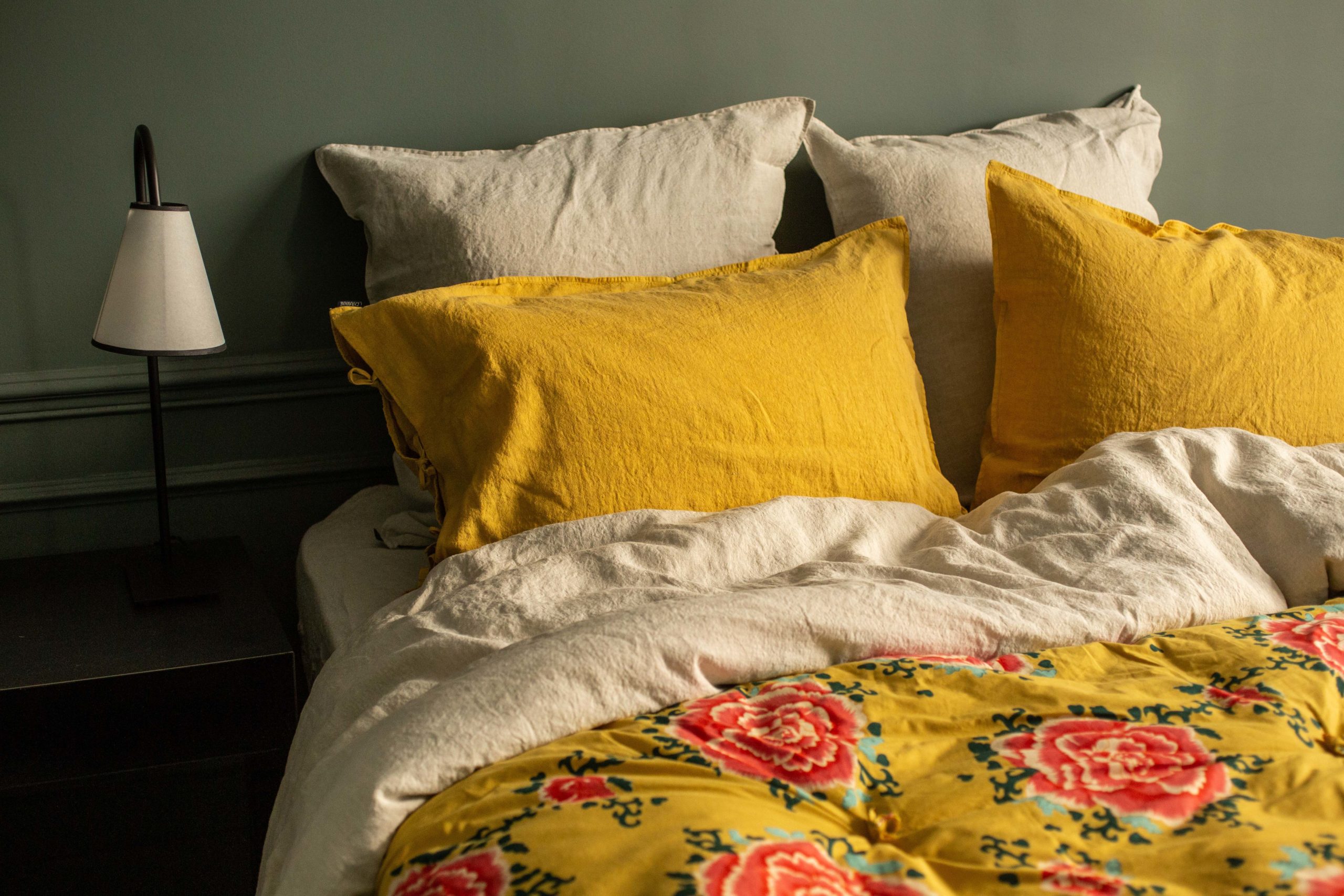 Bed with Caravane yellow linen pillowcases and yellow and pink floral bedspread
