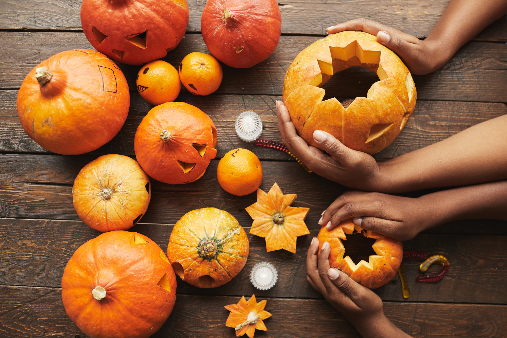 Halloween - From above view shot of hands holding pumpkin for Hallowing party on dark brown wooden table