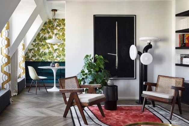 Living area with two chairs, green pattenered kitchen in background