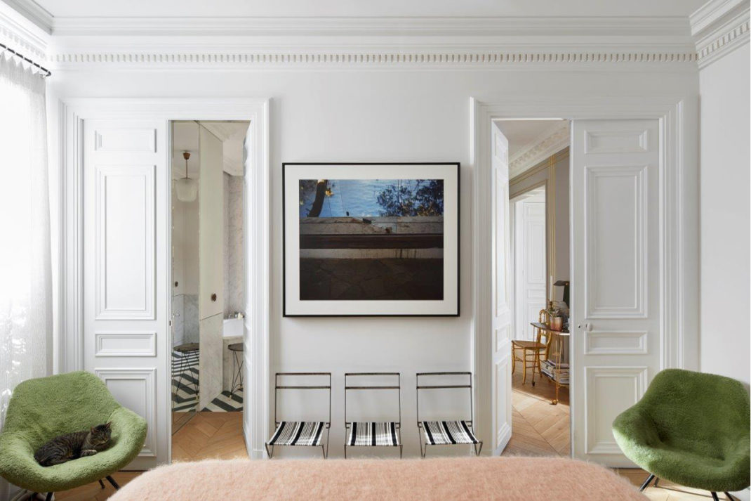 Panelled white room with two doors and two green chairs