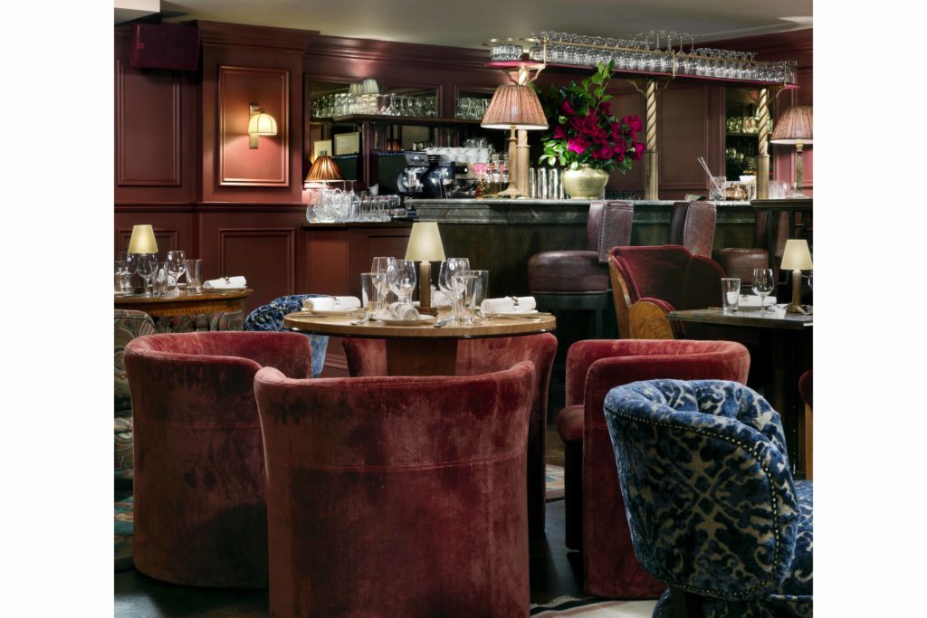 The Ned Parlour with red velvet armchairs and bar