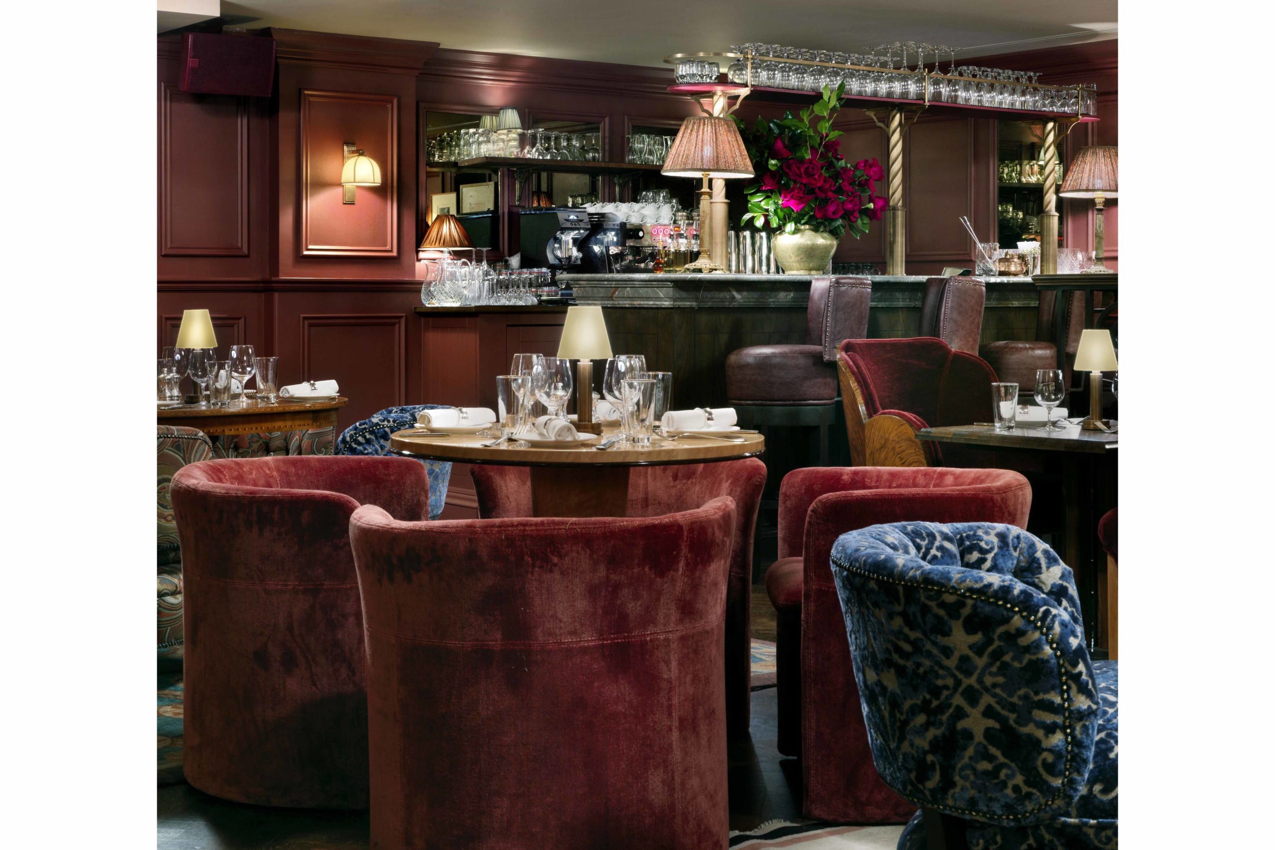 The Ned Parlour with red velvet armchairs and bar