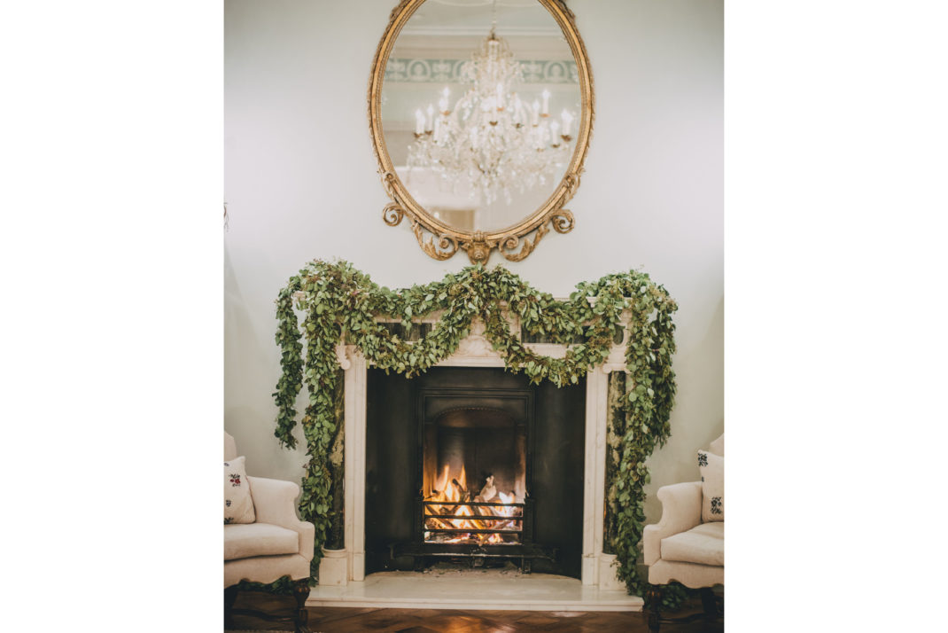 Kitten Grayson foliage decorated fireplace with gold mirror hanging above