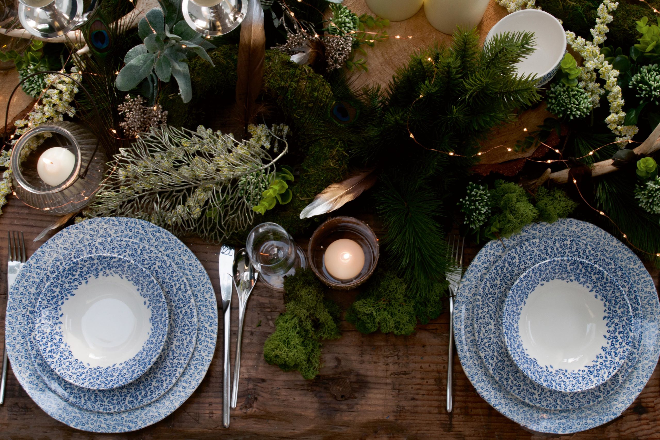 Two Burleigh blue and white china table settings with greenery centrepiece