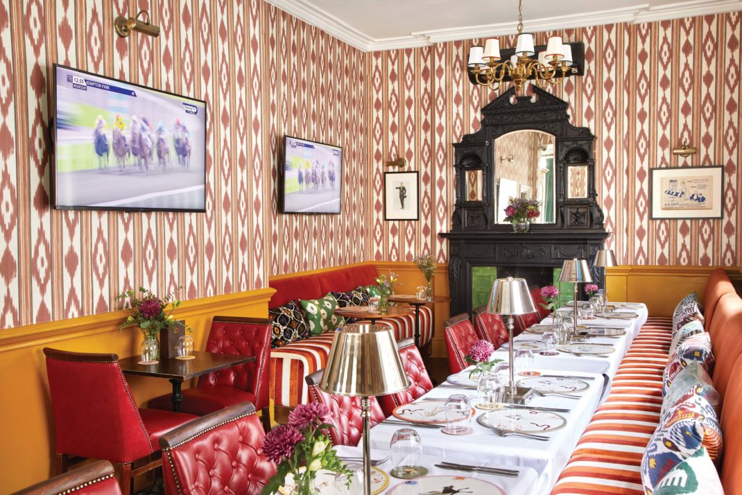The Fitzdares Club dining room with read leather seating, tables and red patterned wallpaper