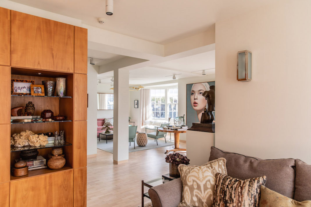 Wendy Goldsmith's home: open plan sitting room with wooden shelves, modern art on the walls