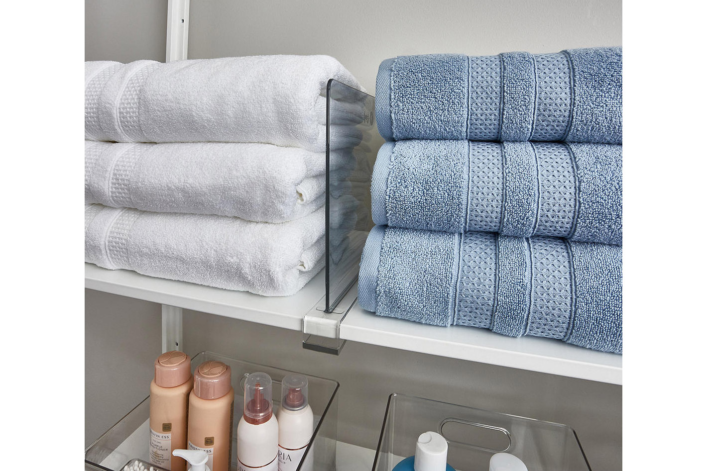 Clear acrylic shelf dividers separating a pile of blue and white towels