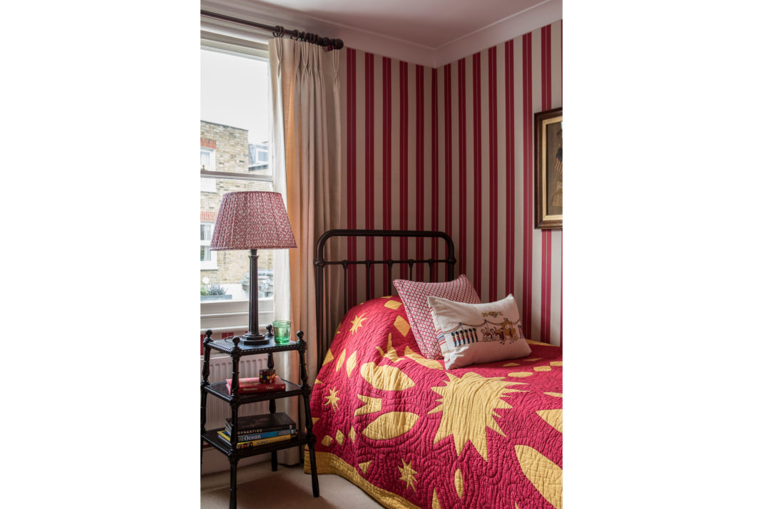 Bedroom with red and white stripe wallpaper, single bed and lamp