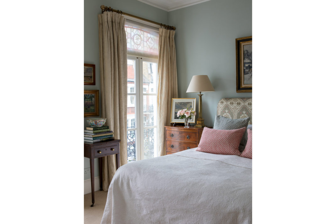 Bedroom with green walls, double bed and side table