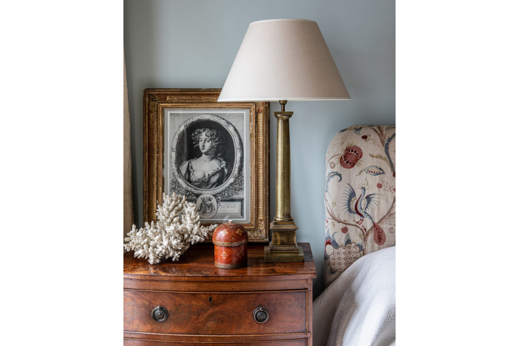 Bedside table detail with lamp, wooden table and patterned headboard