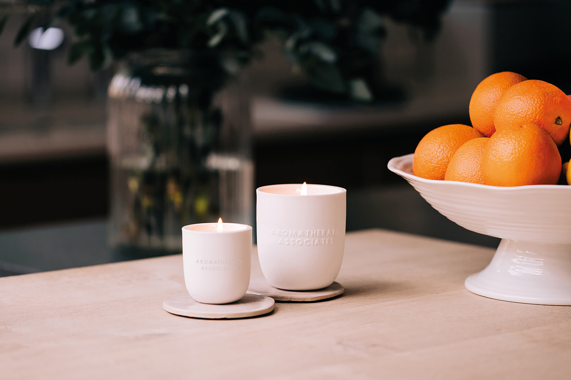 Candles on table with bowl of oranges