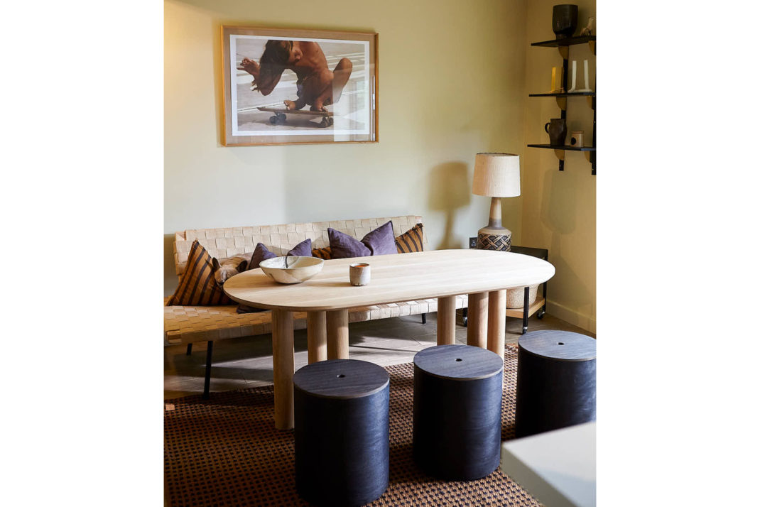 Modern sitting room, black stools, dining table, art print in background