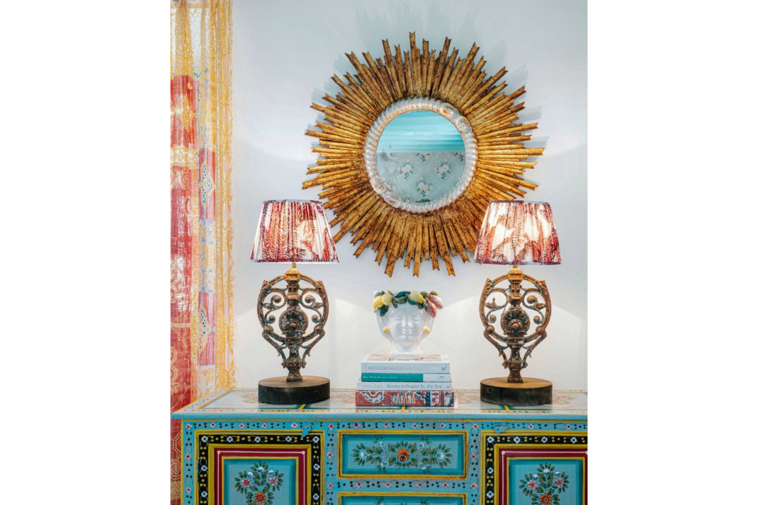 Two colourful lamps on turquoise table. Sunburst bronze mirror behind.