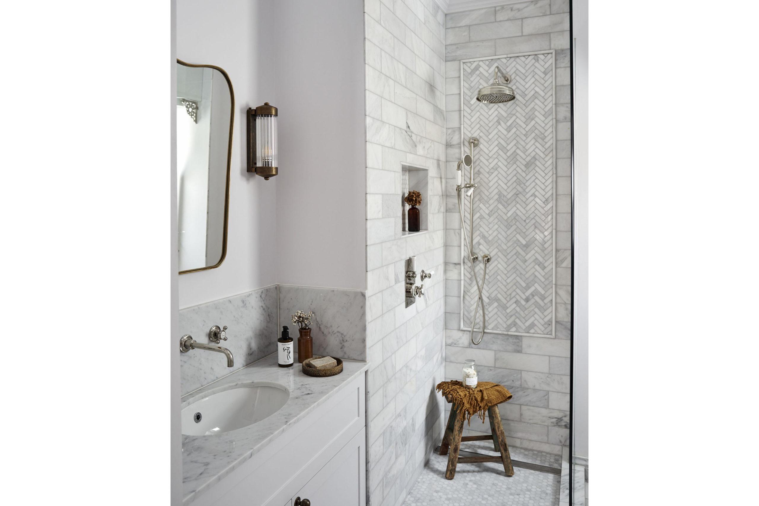 White bathroom. Marble tile shower and sink with mirror hanging above.