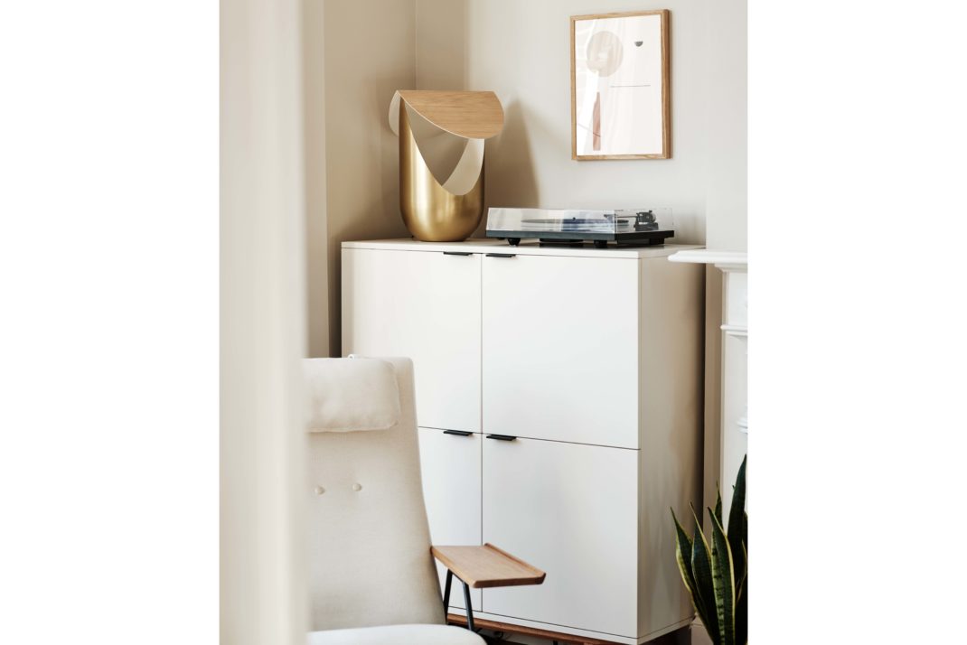White cabinets, white modern chair, bronze modern sculpture, art print in background.