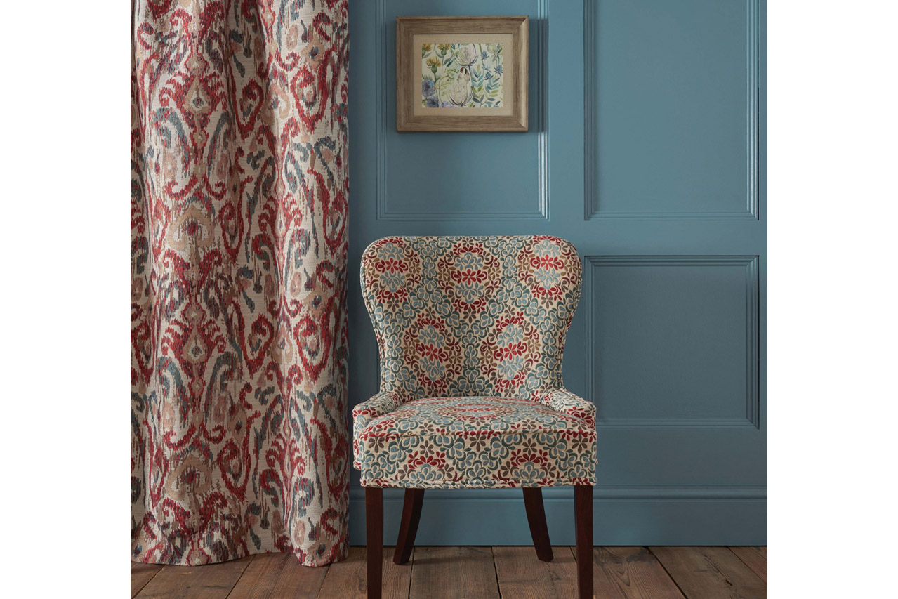 Osborne & Little red green patterned chair and curtain blue wall