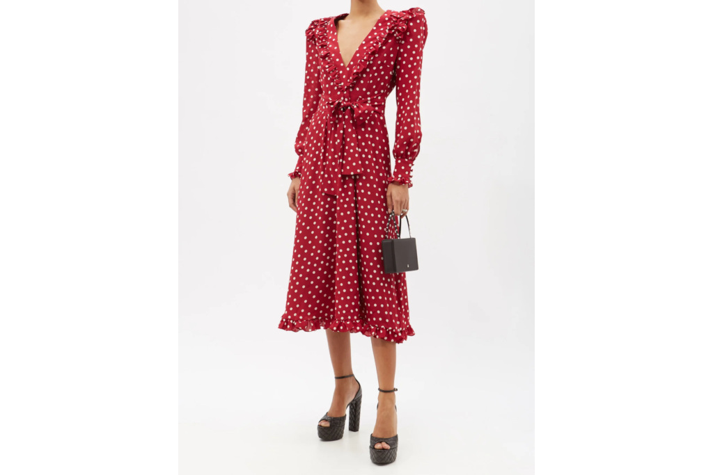 Woman in red polka dot midi dress, holding a black handbag and wearing black platform heels