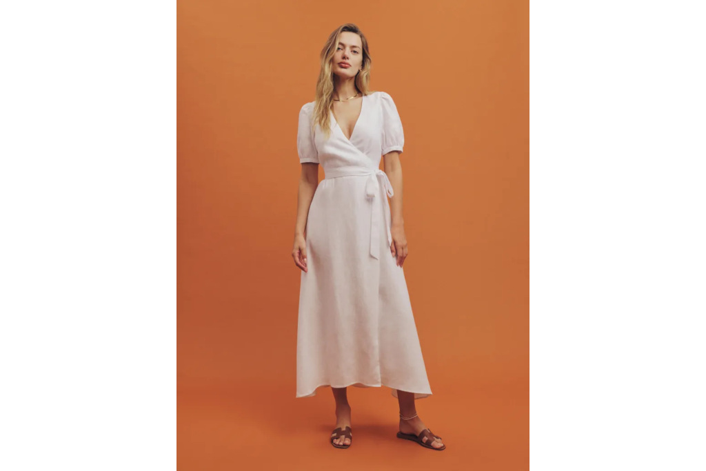 Woman in white dress stood in front of orange background