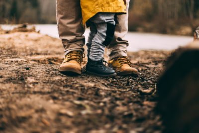 Man stood with child, only feet in hiking boots visible