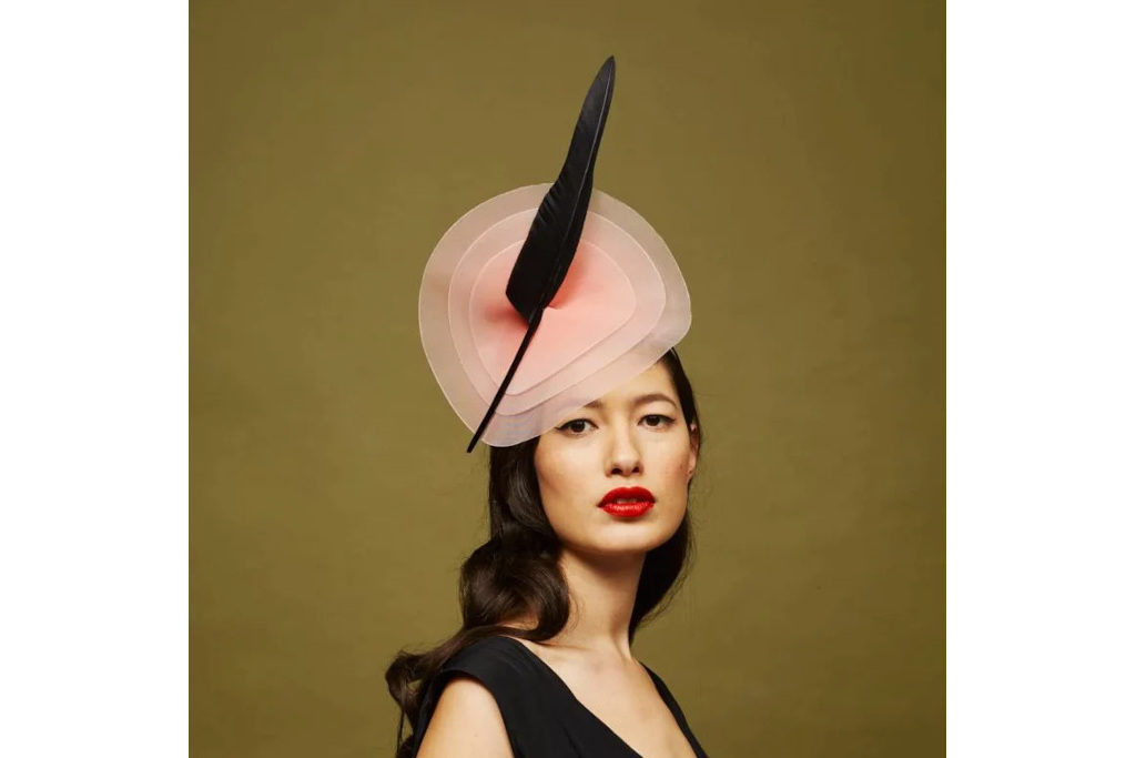 Woman wearing pink hat with black feather