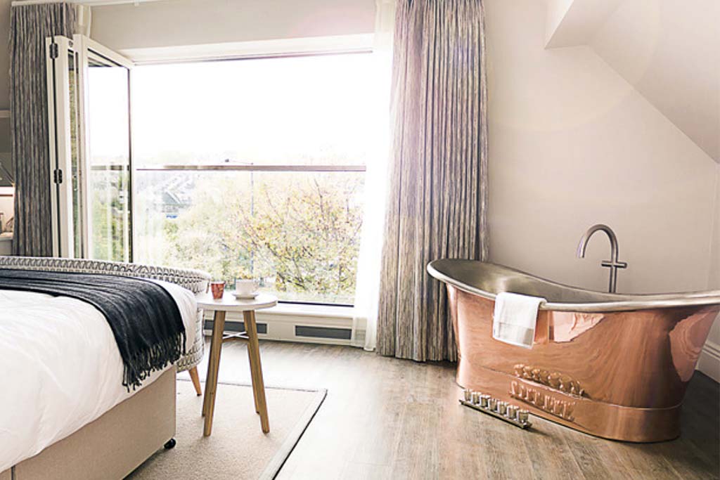Hotel room with copper bath, large bed and balcony