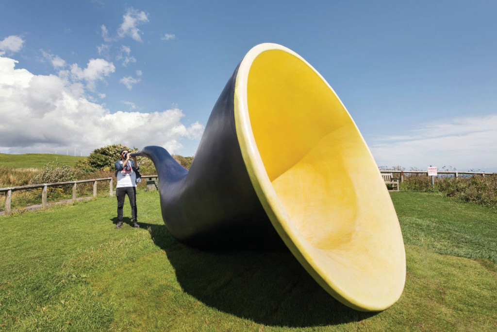 A man blows on a giant horn