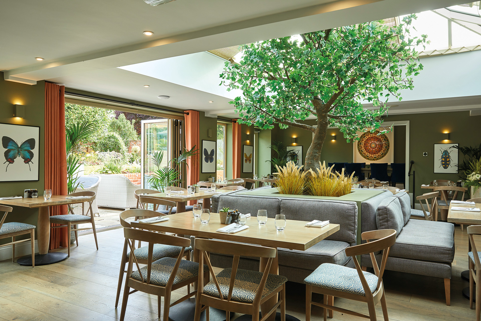 Foyer of the Royal Oak, Yattenden, with wooden tables and a tree and skylight in the centre.