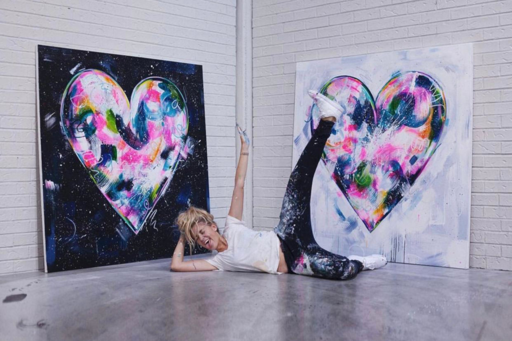Sophie Tea lies in front of her paintings