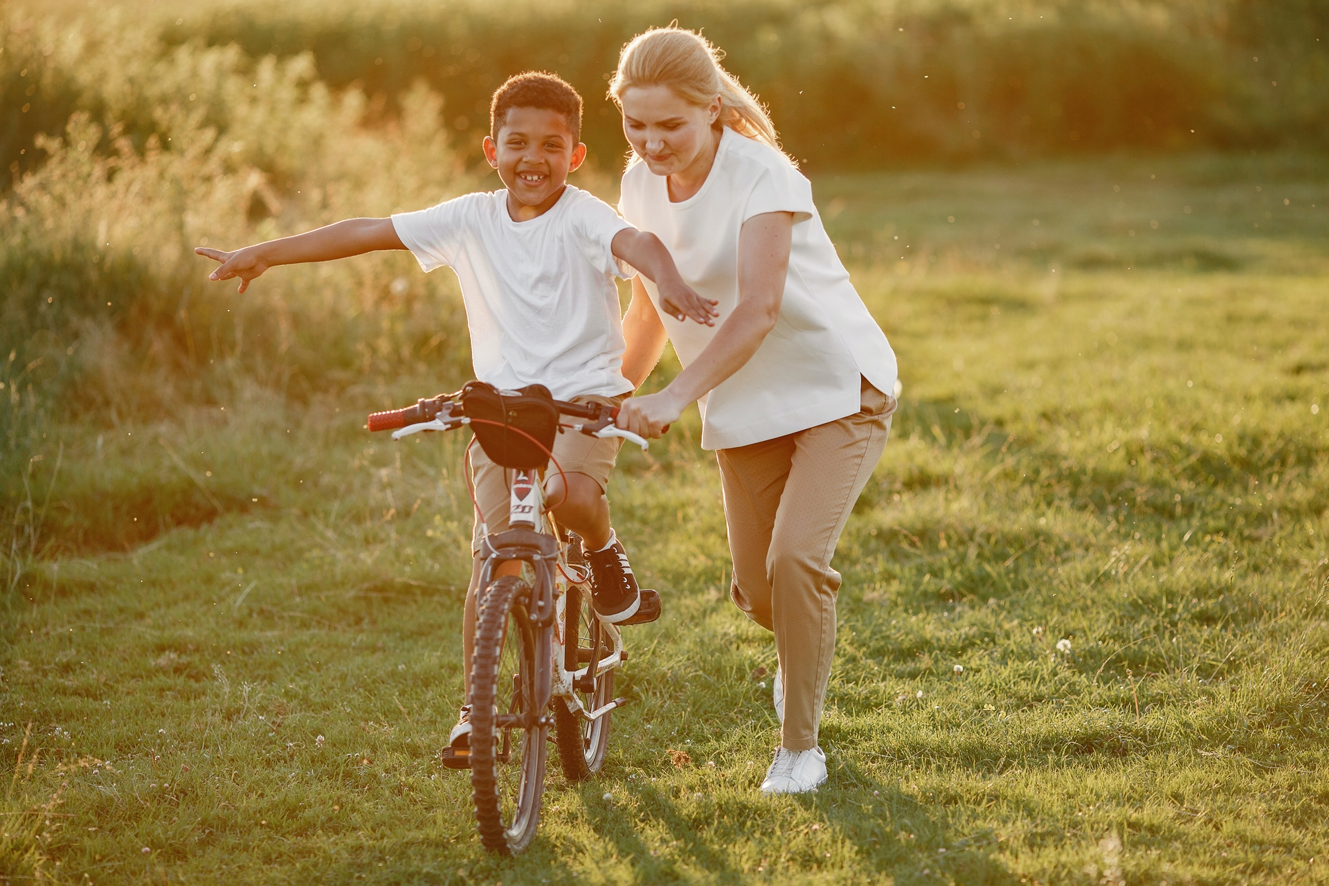 A young boy learning how to ride a bike in a field