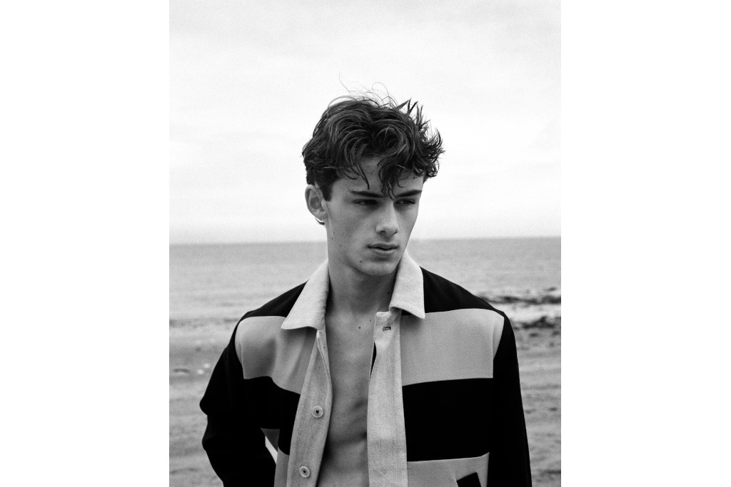 Male model in unbuttoned striped shirt on the beach