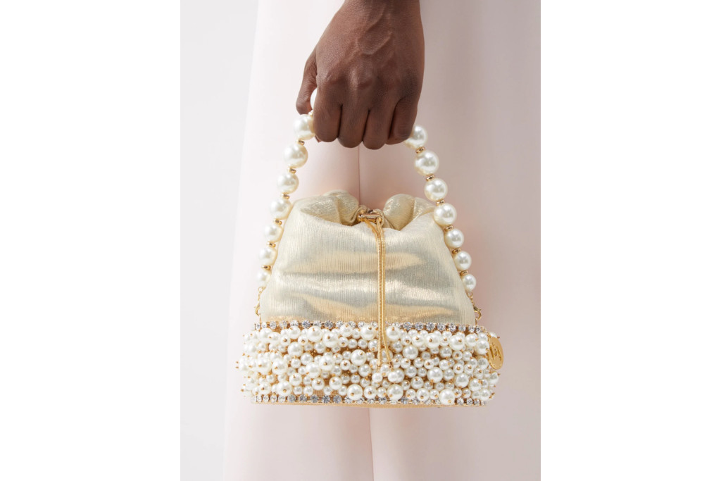 Hand holding faux pearl clutch bag