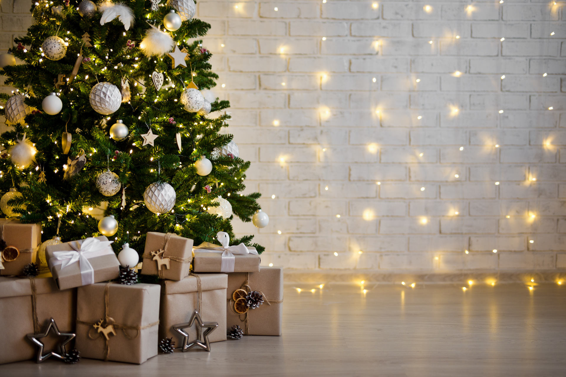 christmas tree and heap of gift boxes - copy space over white brick wall with lights