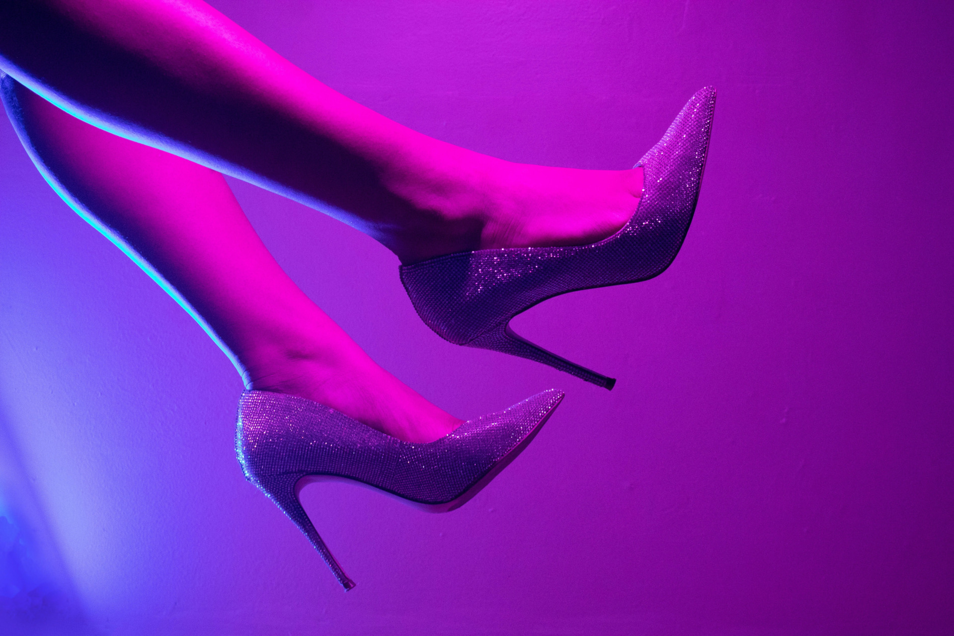 Close up of legs and feet wearing glittery shoes in purple light