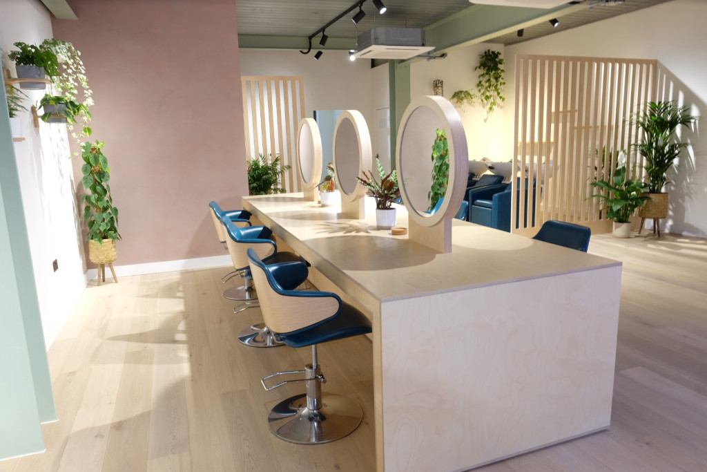 View of a salon with blue chairs and circular vanity mirrors