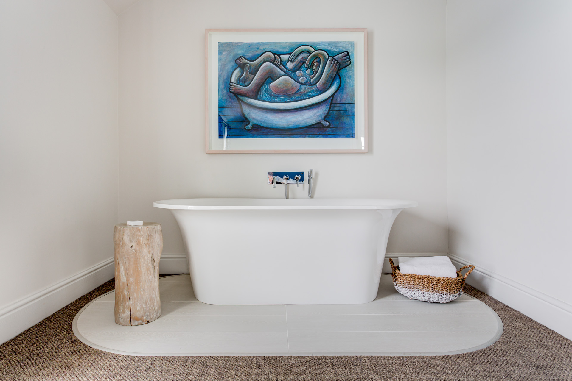a freestanding bathtub with a painting above it