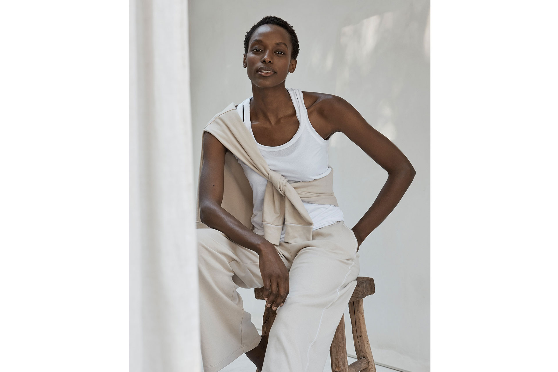a woman sits down wearing cream Bamford yoga clothing